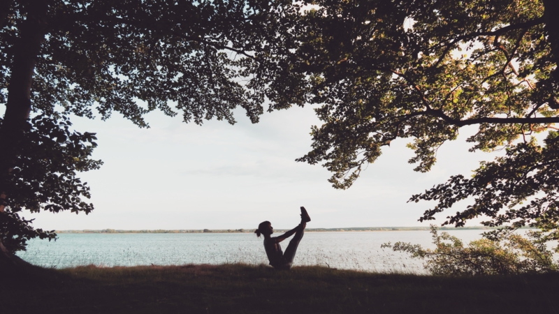 Caro macht Pilates in der Natur vor einem See